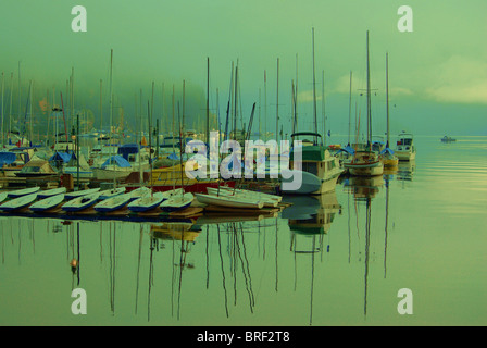 Petit port de plaisance sur matin brumeux de mâts de voiliers en réfléchissant sur la surface de l'eau était claire. Banque D'Images