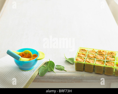 Les aliments pour bébé purée de carottes dans un bol avec masher et pommes de terre et d'épinards à la noix de coco purée Banque D'Images