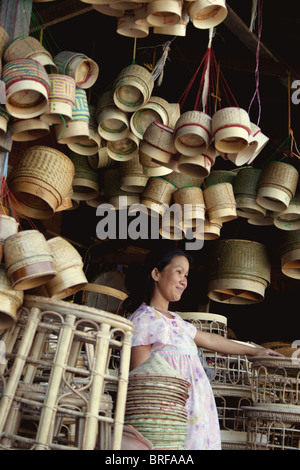 Une femme qui travaille comme vendeur de panier de riz tend à sa boutique à un marché à Vientiane, au Laos. Banque D'Images