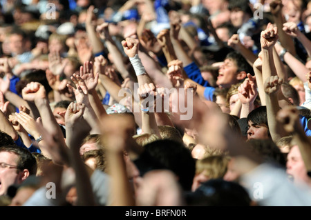 Les spectateurs de football match lever leurs mains en l'air à l'appui de leur équipe Banque D'Images