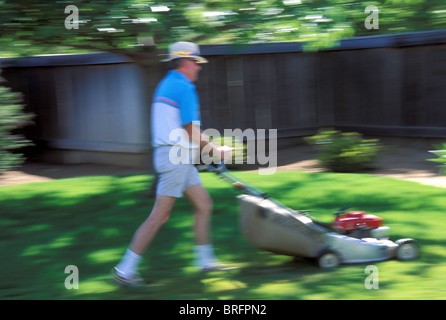 Man Mowing sa pelouse suburbaine bien entretenue avec une tondeuse à gaz, États-Unis Banque D'Images