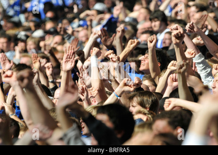 Les spectateurs de football match lever leurs mains en l'air à l'appui de leur équipe Banque D'Images