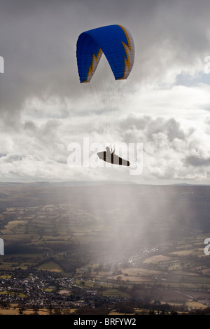 Une personne est suspendue à un parachute parapente-like et flotte dans l'air sur le Sud du Pays de Galles. Banque D'Images