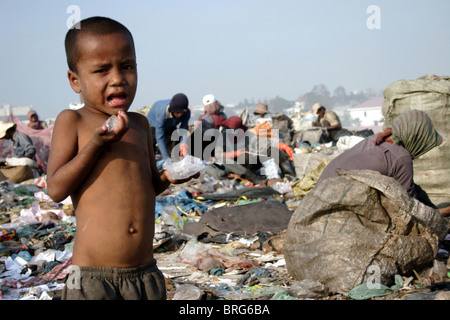 Un jeune garçon qui est un enfant travailleur prend le temps de vous rafraîchir à la décharge de Stung Meanchey à Phnom Penh, Cambodge. Banque D'Images