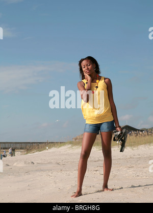 L'un young attractive African American female standing against blue sky sur la plage à très chaud ou malheureux Banque D'Images