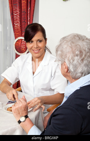 Une infirmière gériatrique aider Senior citizen au petit déjeuner Banque D'Images