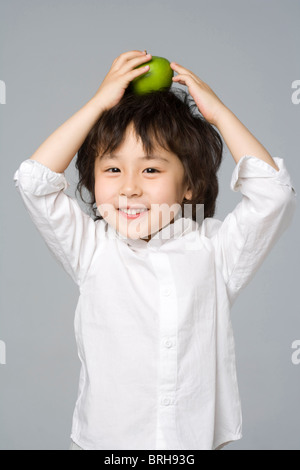 Boy balancing une pomme sur la tête Banque D'Images