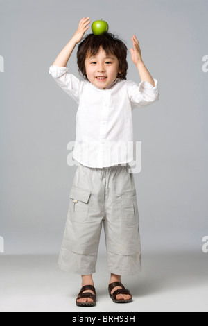 Boy balancing une pomme sur la tête Banque D'Images