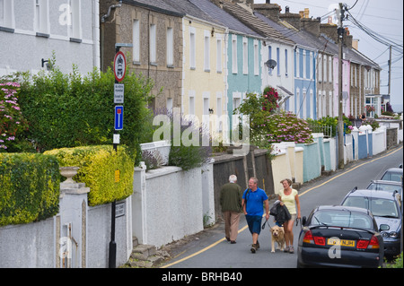 Personnes marchant chien le long passé de la rue terrasse de maisons de la station balnéaire de Gallois Ceredigion New Quay West Wales UK Banque D'Images