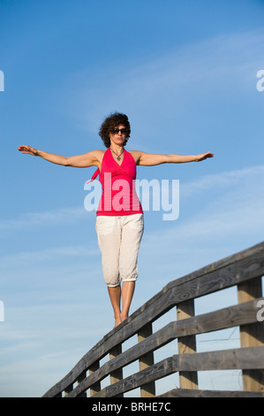 Woman Balancing sur balustrade de bois, Honeymoon Island State Park, Florida, USA Banque D'Images