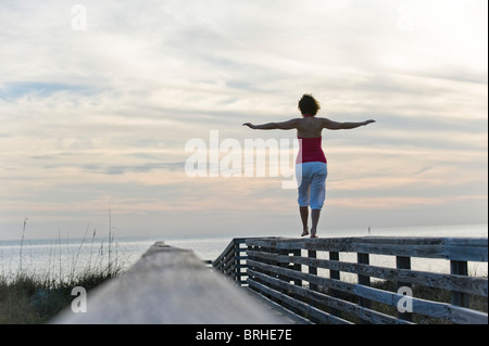 Woman Balancing sur balustrade de bois, Honeymoon Island State Park, Florida, USA Banque D'Images