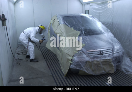 Un homme dans une cabine de peinture de pulvérisation fonctionne sur une réparation de voiture UK Banque D'Images