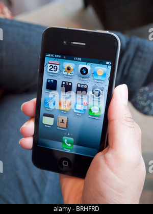 Femme tenant l'iPhone 4G Téléphone intelligent sur l'écran d'accueil Banque D'Images