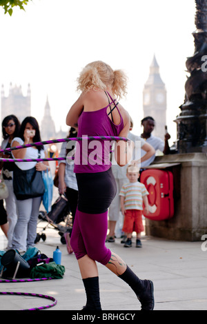 La Hula Hooper Lisa Lotti effectue sur London's South Bank avec Big Ben en arrière-plan. Banque D'Images