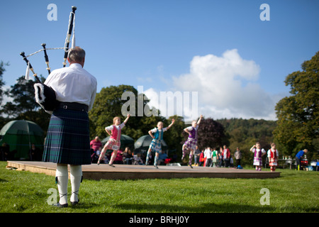Un homme joue de la cornemuse pour jeunes danseurs écossais Peebles, les Jeux des Highlands, Ecosse, Royaume-Uni Banque D'Images