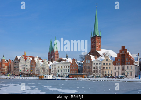 Les églises Saint Petri et Saint Mary s'élevant au-dessus des maisons le long de la rivière Trave, gelé en hiver, Allemagne Luebeck Banque D'Images