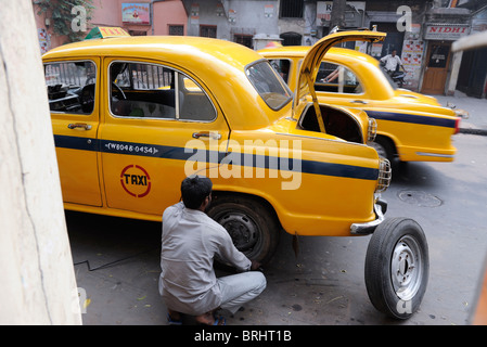 Asie du Sud Inde Calcutta Kolkata , chauffeur de taxi réparer un pneu à plat avec cabine , Ambassadeur voiture qui est basé sur le modèle britannique Morris Oxford Banque D'Images