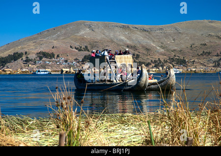 Un bateau fabriqué à partir de roseaux totora emmène les touristes pour une balade à l'île flottante d'Uros, Lac Titicaca, Puno, Pérou. Banque D'Images