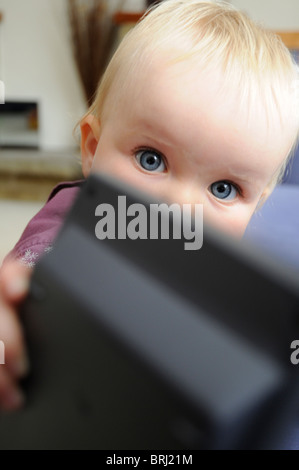 11 mois vieux blue-eyed baby girl en passant un objet Banque D'Images