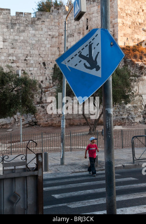 Israël. Jérusalem est. près de la porte de Damas. Boy crossing road à passage piéton avec de bkgd Banque D'Images