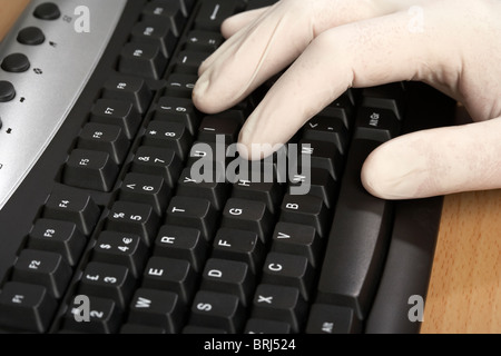 port manuel de gants chirurgicaux blancs en caoutchouc gant dactylographie au clavier d'un ordinateur protection contre l'infection ou concept de sécurité Banque D'Images