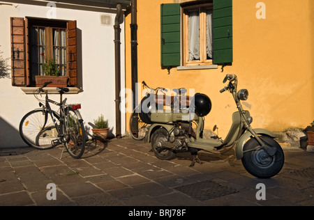 Scène de rue avec les vélos et les motos, centre historique de Caorle, Veneto, Italie Banque D'Images