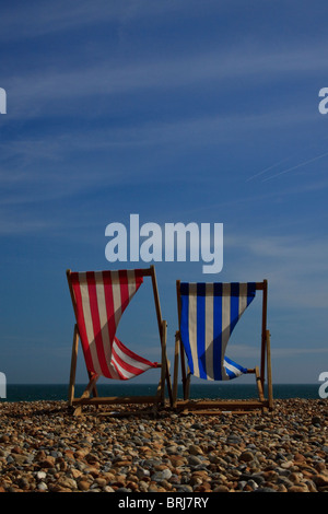 Deux chaises longues sur la plage de Brighton contre un ciel bleu clair sur une breezy day Banque D'Images