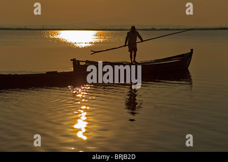 Silhouette de pêcheur sur son bateau au coucher du soleil. Lac Albufera, Parc National, Parc Naturel, Valence, Communauté Valencienne, Espagne Banque D'Images