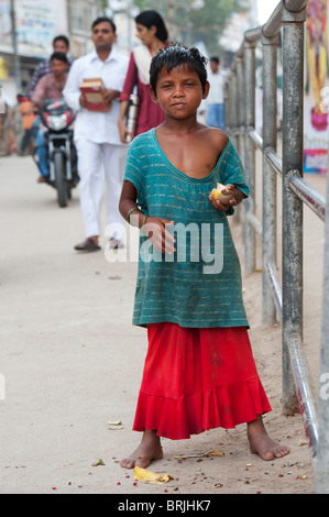 Jeune fille pauvre mendiant indien debout sur le côté de la rue un indien en mangeant des fruits. L'Inde Banque D'Images