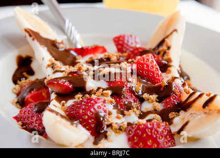 Une assiette santé de banana split avec du yogourt faible en gras, les fraises et sucre ajouté Banque D'Images