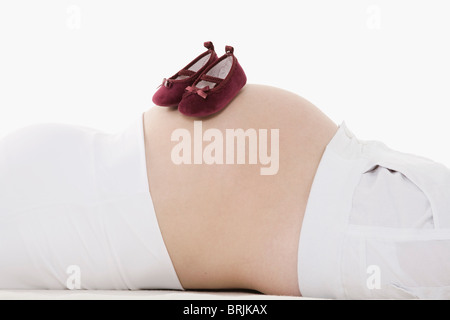 Chaussures bébé sur le ventre de femme enceinte Banque D'Images