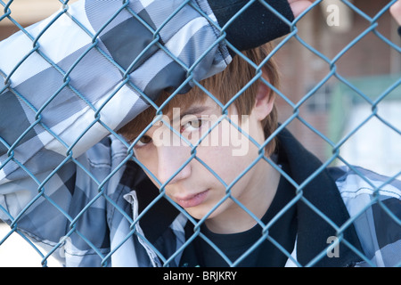 Teenage Boy derrière Fence Banque D'Images