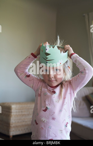 Petite fille le matin de Noël portant une couronne de papier Banque D'Images