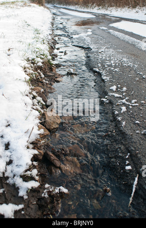 Poule dans une route de campagne causés par la neige et le temps de gel de la fonte des neiges l'écoulement Banque D'Images