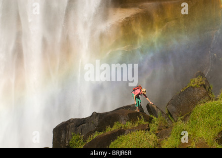 Une jeune femme explore sous une cascade géante. Banque D'Images