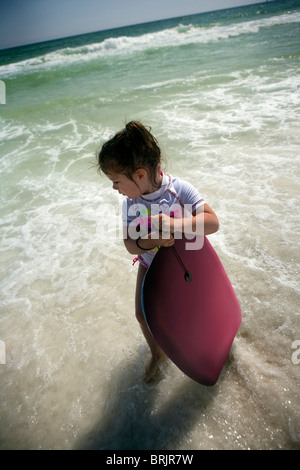 Une petite fille est maintenant un organisme de sélection dans l'océan, près de la rive. Banque D'Images