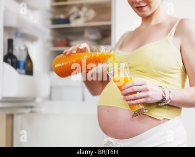 Pregnant woman drinking orange juice Banque D'Images