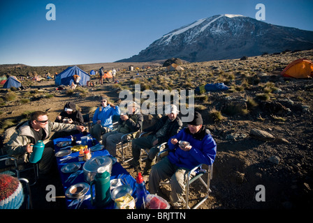 Une équipe de randonneurs ont un bon petit déjeuner au lever du soleil d'environ 1000 ft. En dessous du sommet du Mt. Kilimanjaro. Banque D'Images