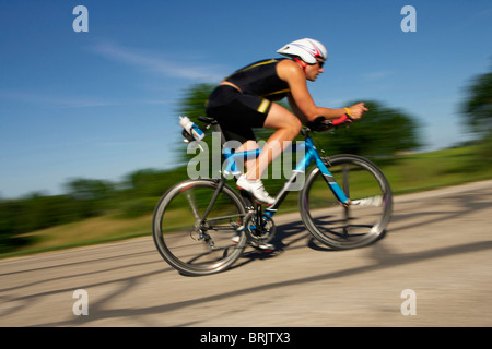 Une formation d'athelete mâle pour un triathlon à un lac sur un vélo. Banque D'Images