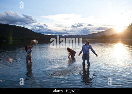Trois jeunes adultes sourire tandis que les projections d'eau au coucher du soleil dans l'Idaho. Banque D'Images