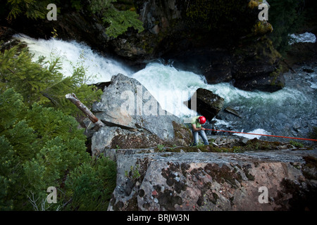 Un jeune homme vers le bas d'une falaise rappels à côté d'une chute dans l'Idaho. Banque D'Images