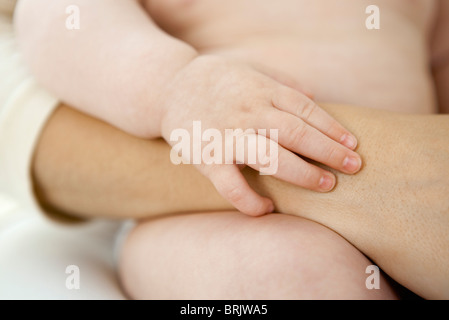 Baby holding mother's arm Banque D'Images