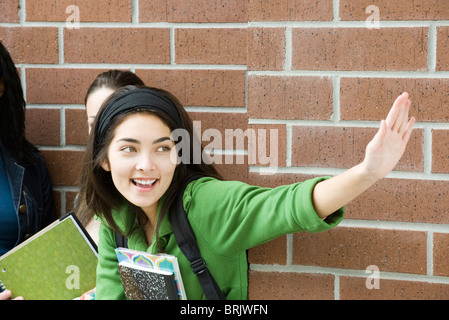 Teenage girl waving to friend Banque D'Images