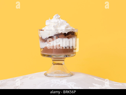 Un solo basse grosse mousse au chocolat avec crème fouettée assis dans un bol en verre sur fond jaune Banque D'Images