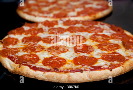 Deux pizzas pepperoni dans une ligne sur une surface noire cuisinière low angle Banque D'Images