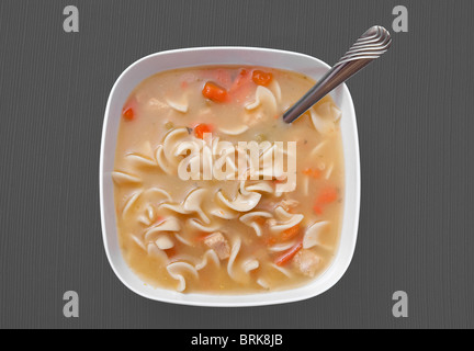 Un simple bol de soupe de nouilles de poulet dans un bol blanc sur fond gris Banque D'Images