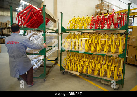 Cadres vélo travailleur tire rack à l'entrepôt d'une usine de vélos Banque D'Images