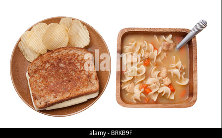 Un sandwich au fromage avec du chips et un bol de soupe au poulet et nouilles maison traditionnelle. la nourriture sur des plats rustiques Banque D'Images