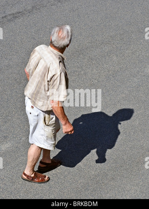 Mature / middle-aged man walking across road - France. Banque D'Images