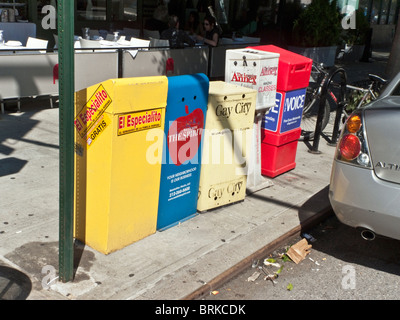 Des distributeurs automatiques de couleur gratuitement journaux alignés sur un trottoir en face de Manhattan westside de sidewalk cafe New York City Banque D'Images